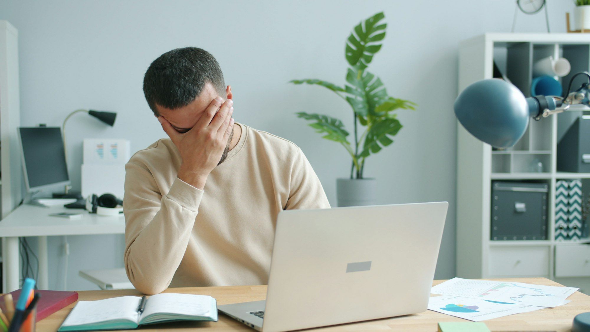 Tired business owner rubbing his face in front of a laptop after a long day