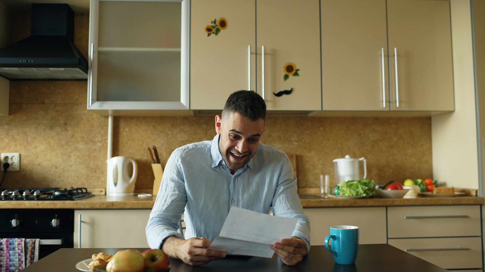 Man at his kitchen table reading a letter with a relieved expression over breakfast
