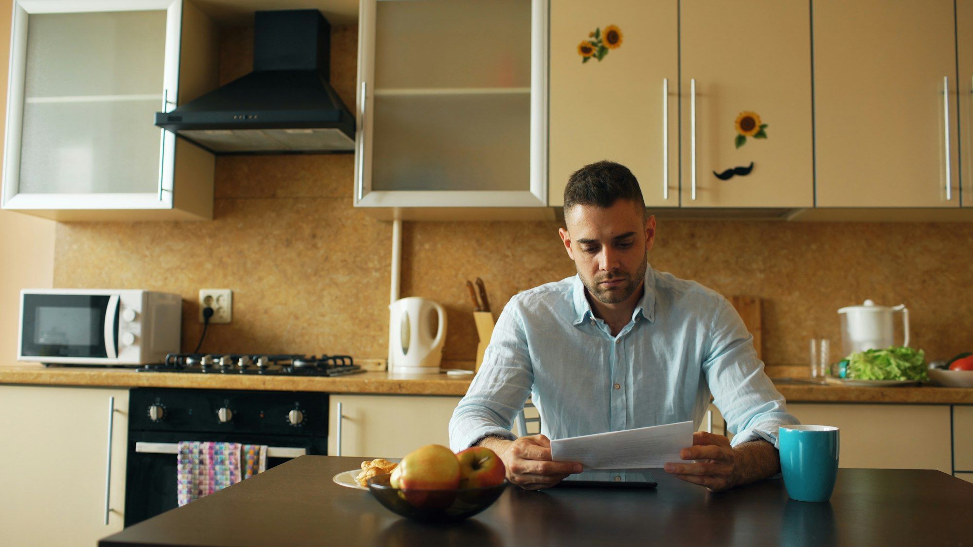 Man reading a demand letter at the kitchen table early in the morning with a coffee