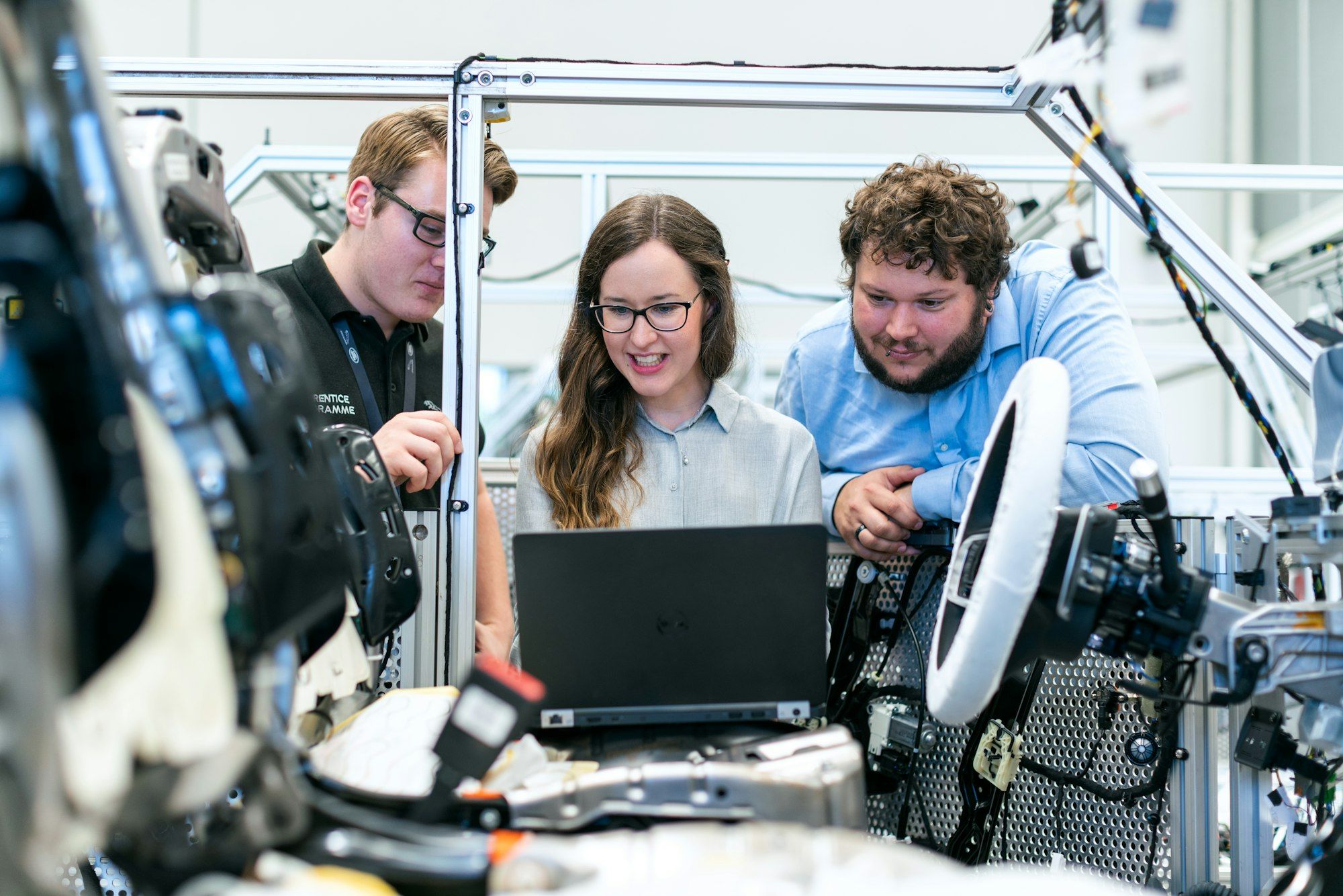 Three people in a workshop looking at a laptop screen together